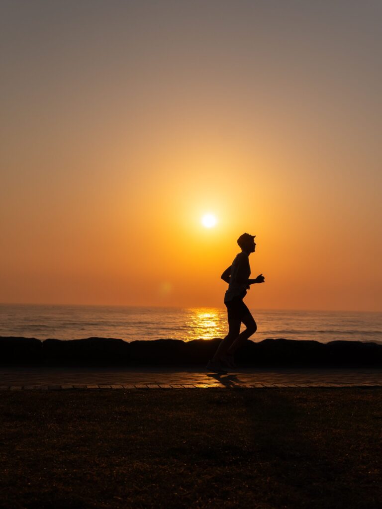 Runner silhouetted against a sunset over the water